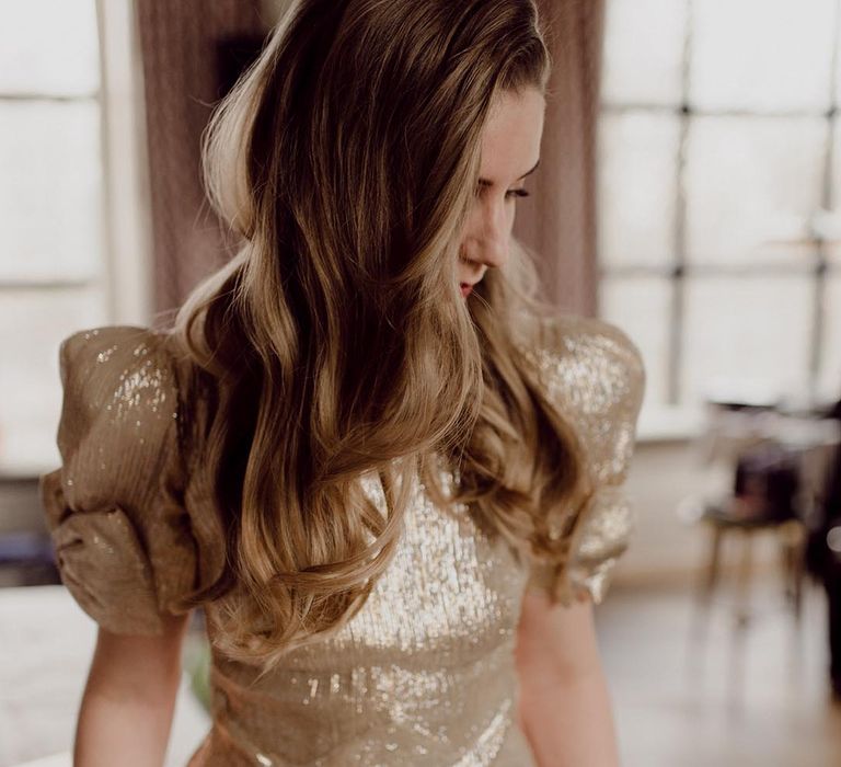 Bride wearing sparkly gold wedding dress with puff sleeves and bow detail for industrial wedding 