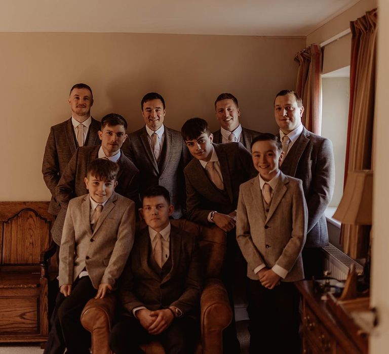 Groomsmen in brown three piece suits and rings bearers in lighter neutral suit for rustic barn wedding 