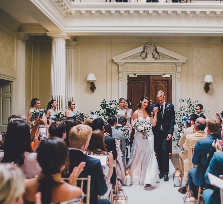 Bride in strapless dress with neutral bouquet and groom in Hedsor House hall 