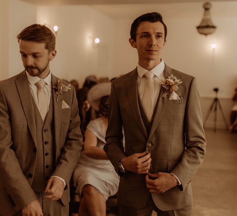 Groom in three piece neutral suit with the best man in matching outfit and dried flower buttonholes 