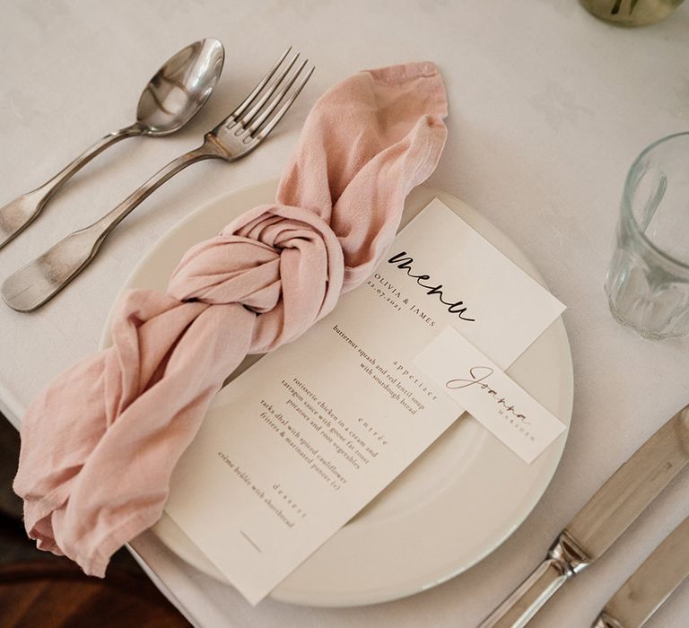 Simple table setting with black and white menu card and place name cards with pink napkin