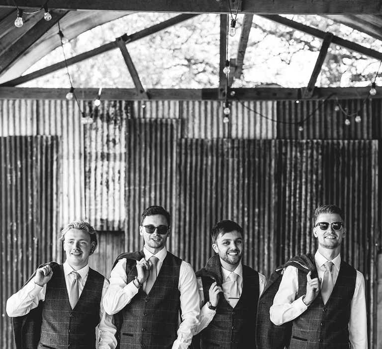 Groom and groomsmen in matching blue checkered suits wearing sunglasses walking together 