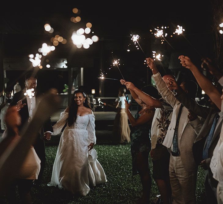 Bride & groom walk through sparkler exit outdoors in Phuket during reception 