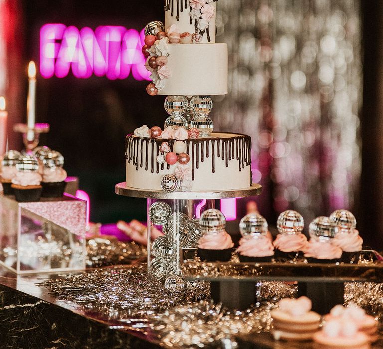 A wedding cake with cool disco ball decorations and matching disco ball cupcakes 