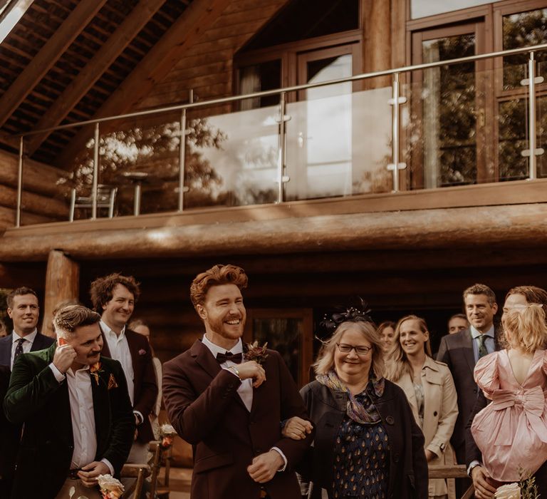 Mother of the groom walks him down the aisle for a rustic autumnal wedding day 