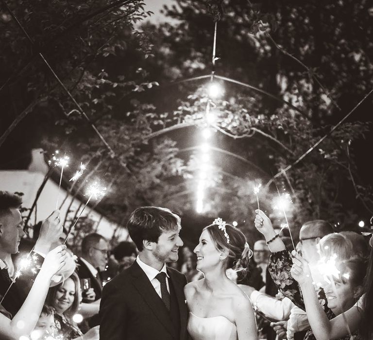 Bride in strapless Suzanne Neville wedding dress with the groom having their sparkler send off