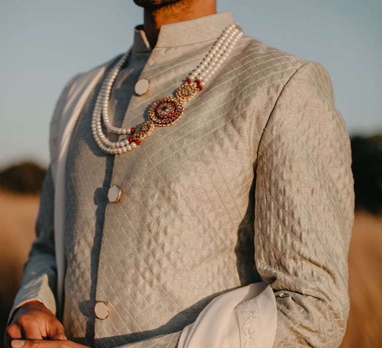 Groom wears pastel sherwani complete with peal necklace and gold embellishment 