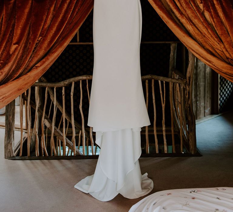 White satin Made With Love wedding dress hanging up 