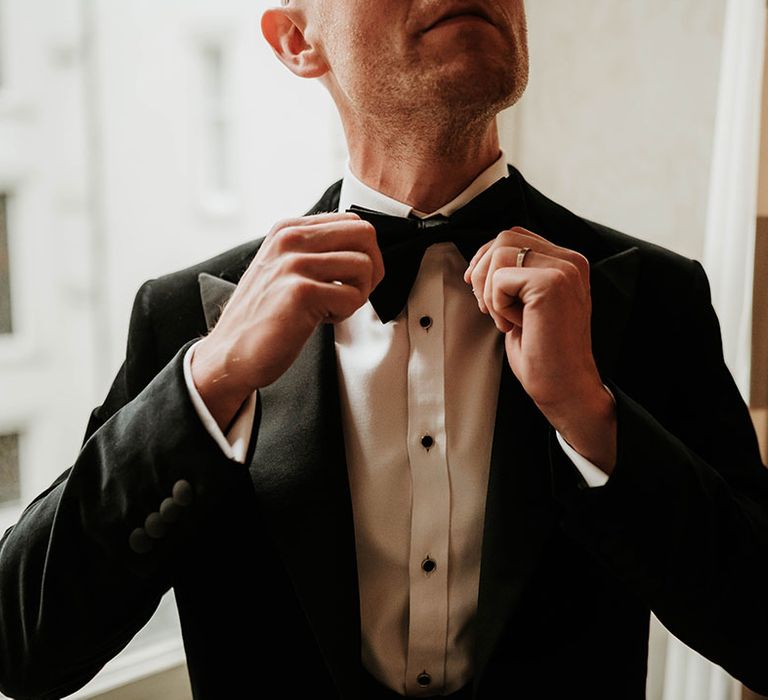 Groom wearing black velvet blazer, white shirt with black button detailing and black bowtie at The Balmoral Edinburgh