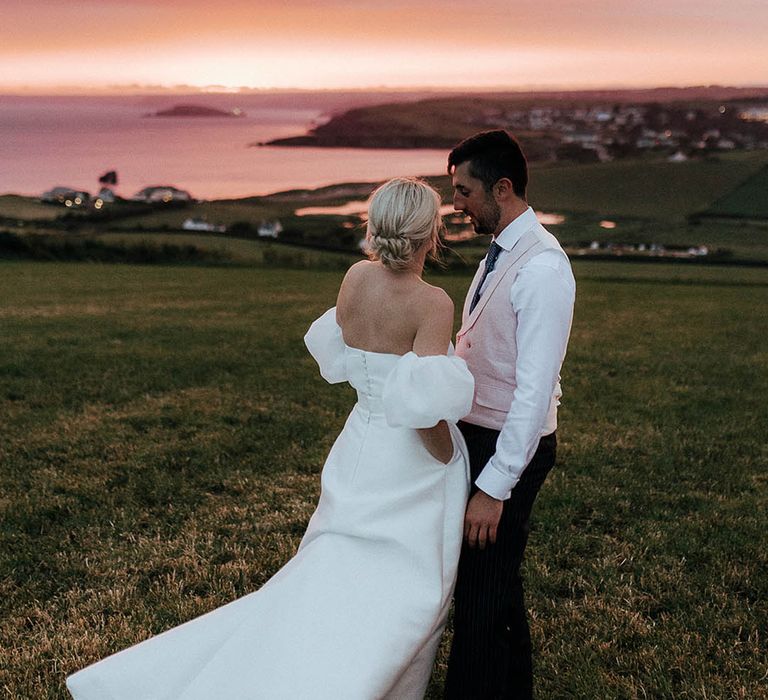 Bride & groom stand outdoors during beautiful sunset for Salcombe wedding beside the sea 