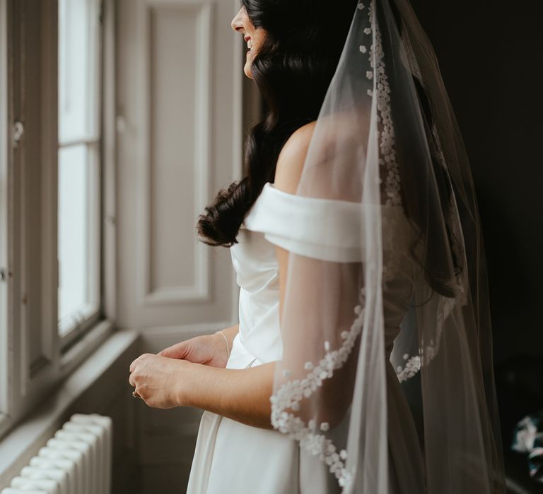 Bride wears floral embellished edge veil in her dark hair 