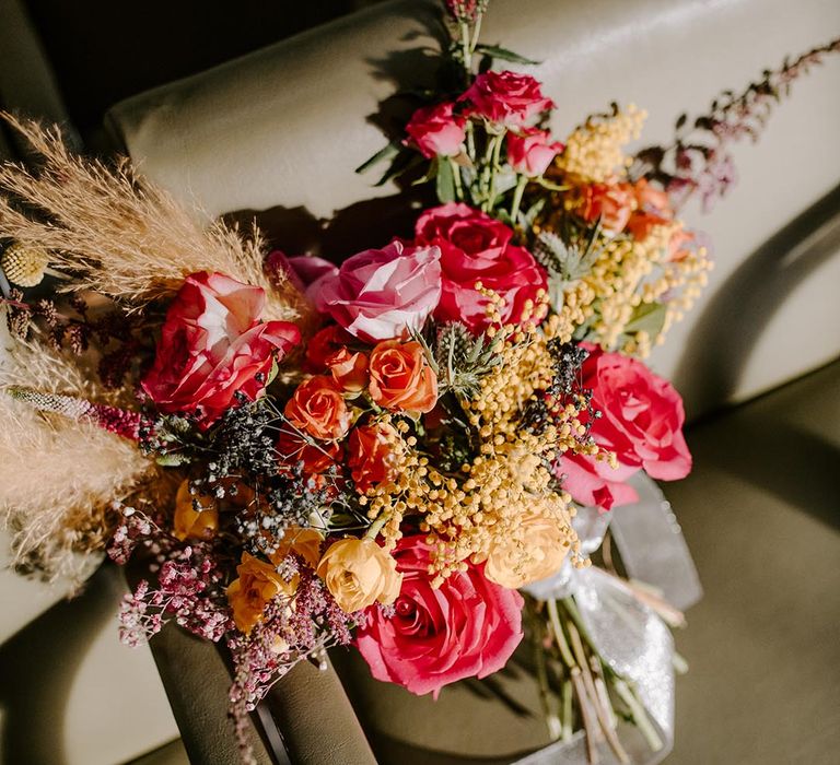 Pink garden rose, pampas grass, carnations, baby's-breath, dried flower and foliage bridal bouquet with sheer white lace ribbon