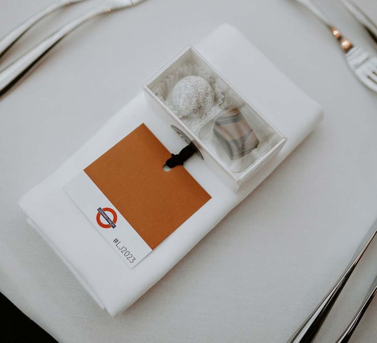 Small cardboard container with two wedding chocolates on white wedding napkin with London tube station tag 