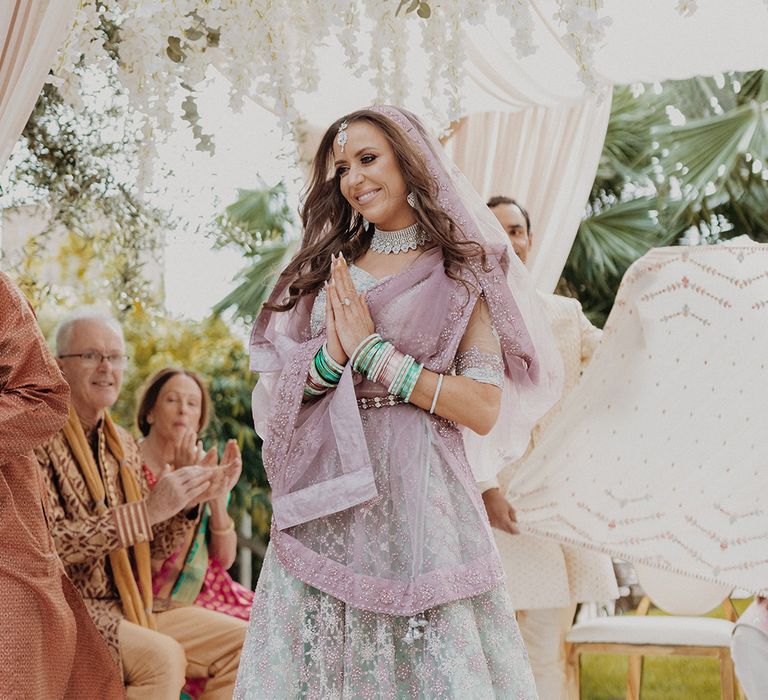 Bride standing inside the wedding mandap wearing mint green and dusky pink ombre embellished lehenga 