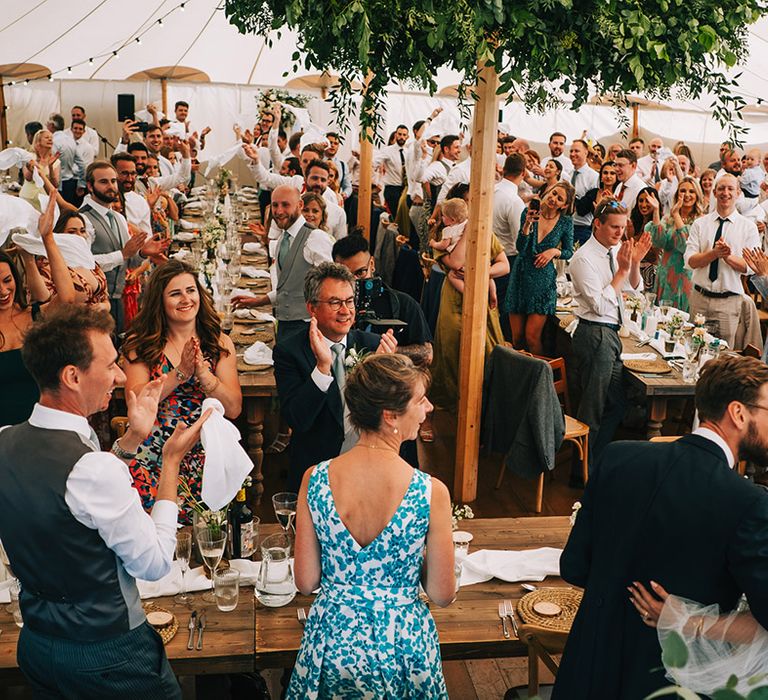 The guests all stand up and celebrate the bride and groom at the wedding breakfast 