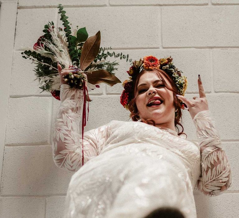 Bride in boho long sleeve 3D applique wedding dress with boho rustic dried flower crown and black platform Dr Martens wedding shoes holding earthy toned garden rose, pampas grass, dried flower and foliage bridal bouquet in The Barn at Avington