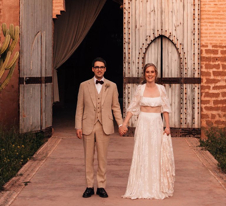 Stunning bride in lace bridal separates with groom in three piece cream suit 