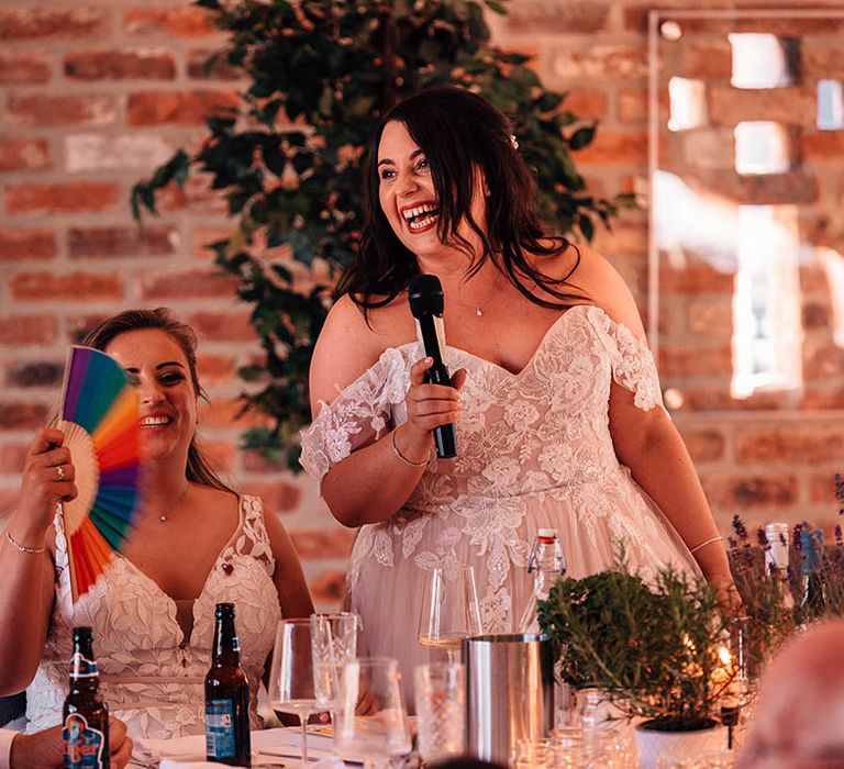 The bride in an off the shoulder wedding dress reads out her bridal speech at the wedding breakfast 