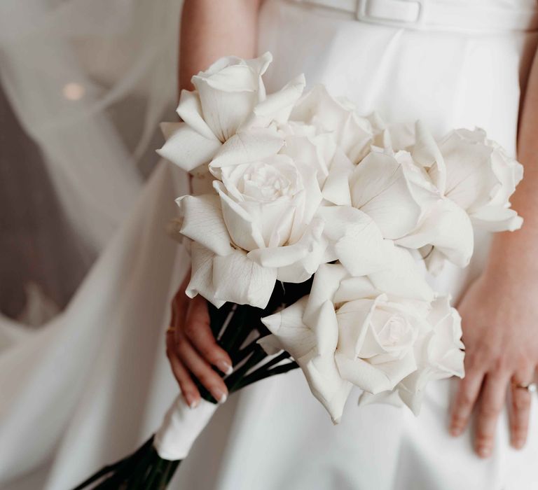 White rose bridal bouquet with long green stems and white ribbon