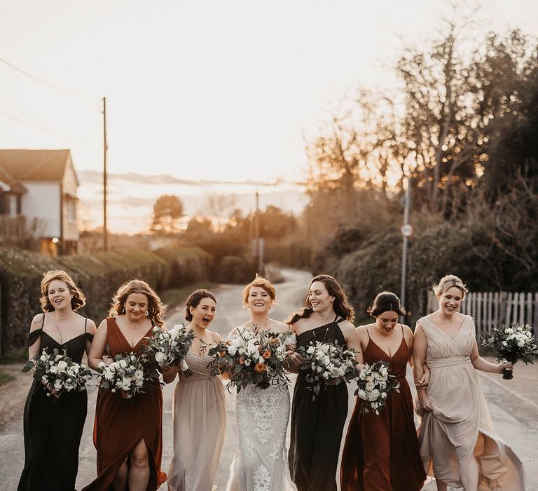 Barn wedding in autumn with the bride and bridesmaids walking together with their matching bouquets