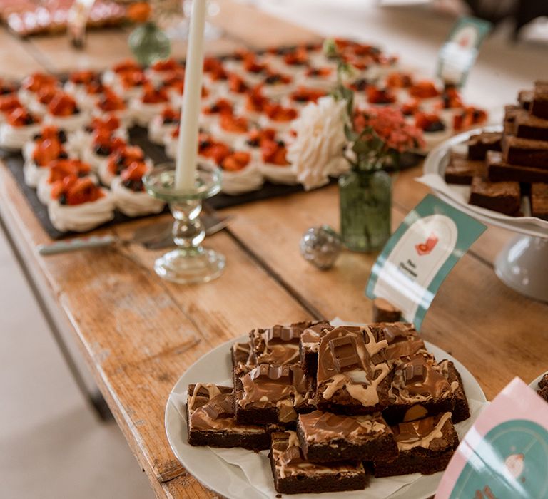 Wedding dessert table full of sweet treats with brownies, cakes and more 