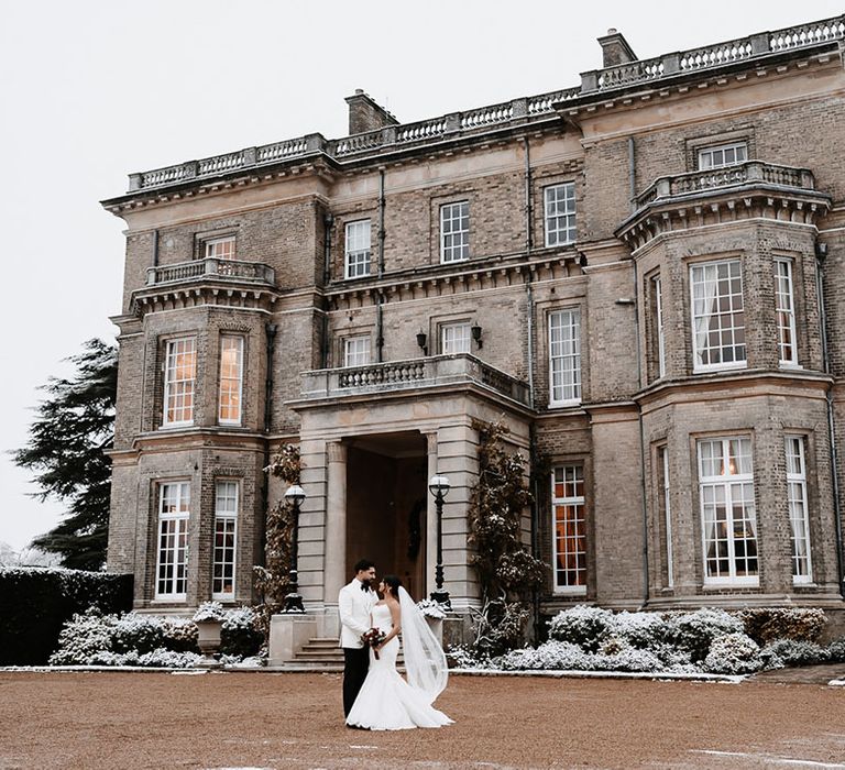 The bride and groom wearing white wedding outfits at Hedsor House country house wedding venue 