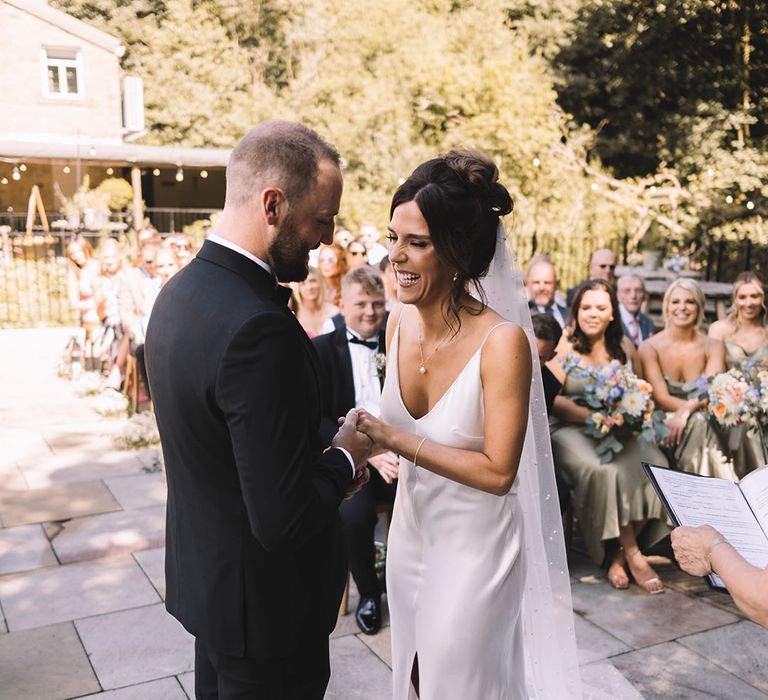 Bride in satin slip wedding dress with the groom in a black tuxedo 