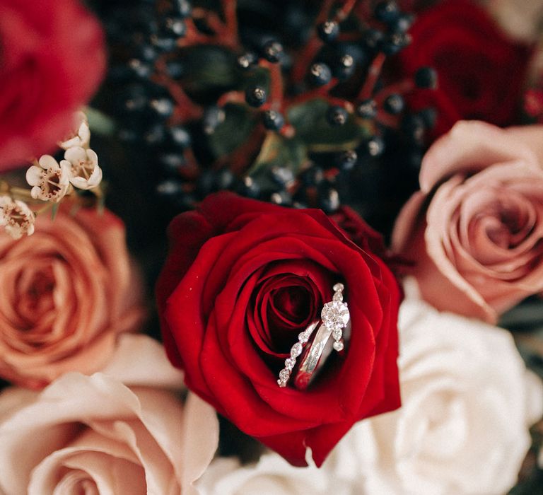 Red and white rose wedding bouquet with diamond engagement ring and wedding band for the bride 