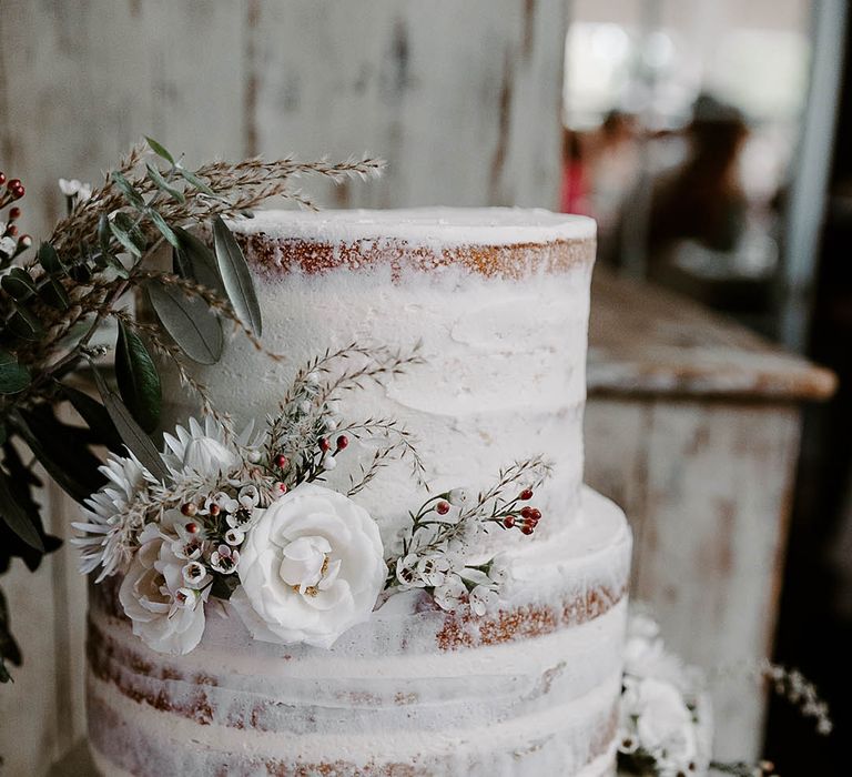 Three tier semi naked wedding cake for modern chic wedding with white flowers and berries 