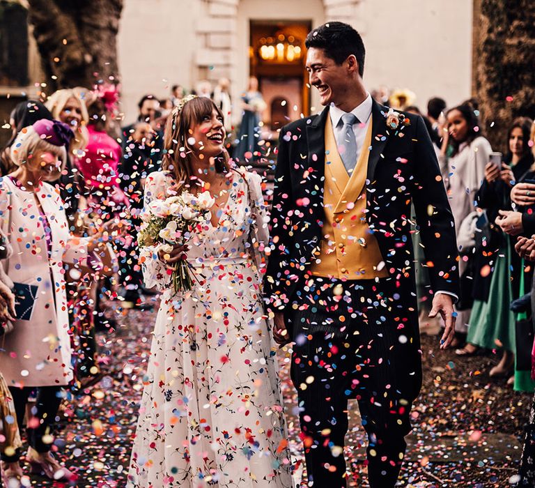 Colourful wedding confetti exit with bride and groom after traditional church ceremony 