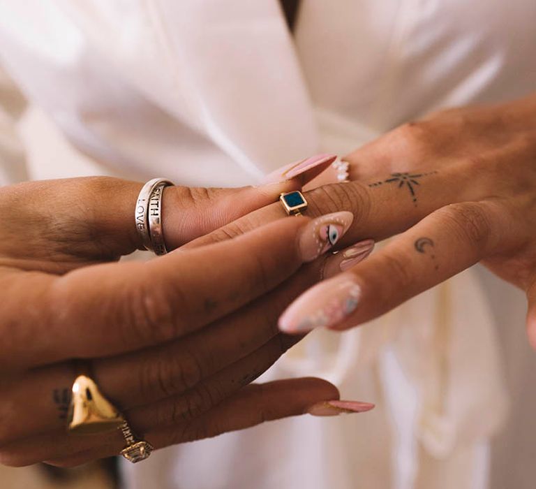 Bride with evil eye design on wedding nails putting on rings and other jewellery 