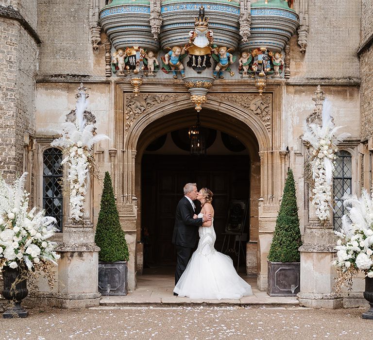 Hengrave Hall grand mansion wedding venue with the bride and groom kissing for their couple portraits 