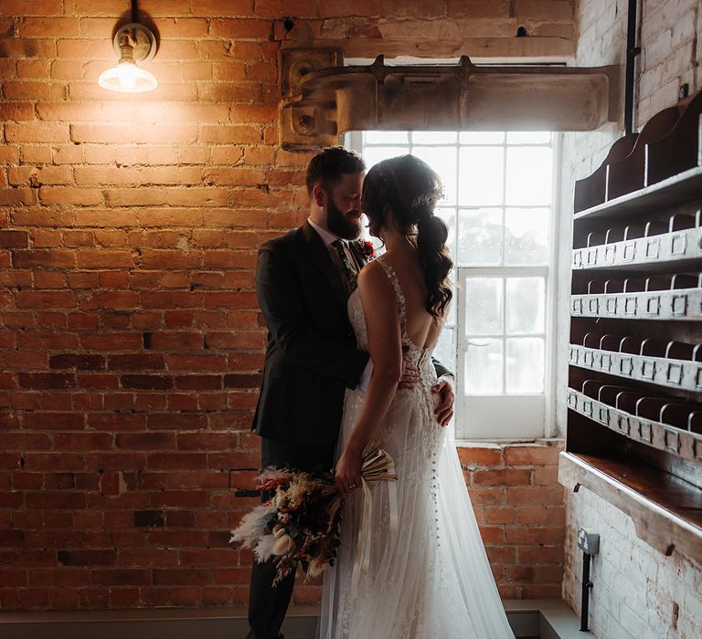 Romantic couple portrait with bride in lace wedding dress gazing at the groom 