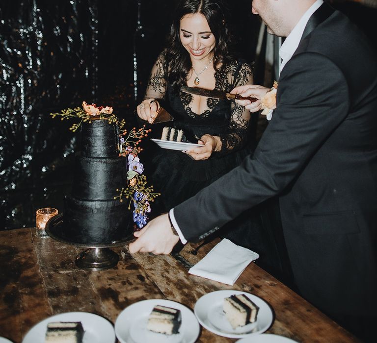 Bride and groom cut their black three tier wedding cake 