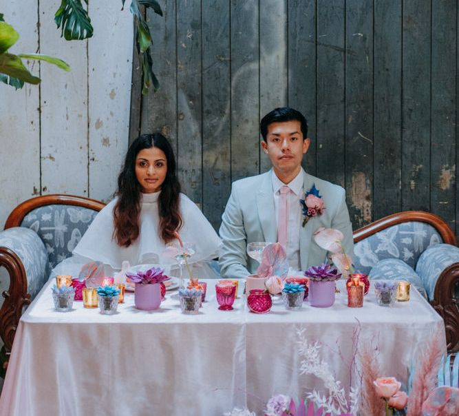 Bride and groom dining at their holographic pastel sweetheart table 