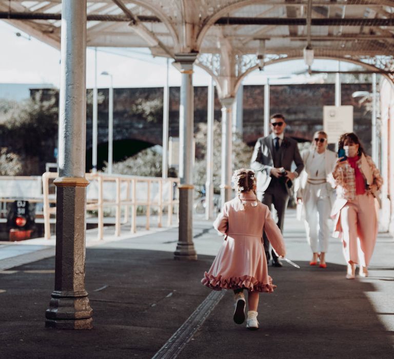 Niece in pink coat rushing to see the bride and groom 