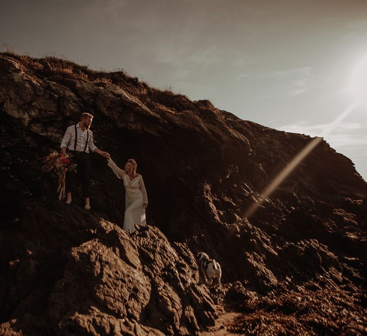 Bride and groom walk along the rocks at Anglesey Island 