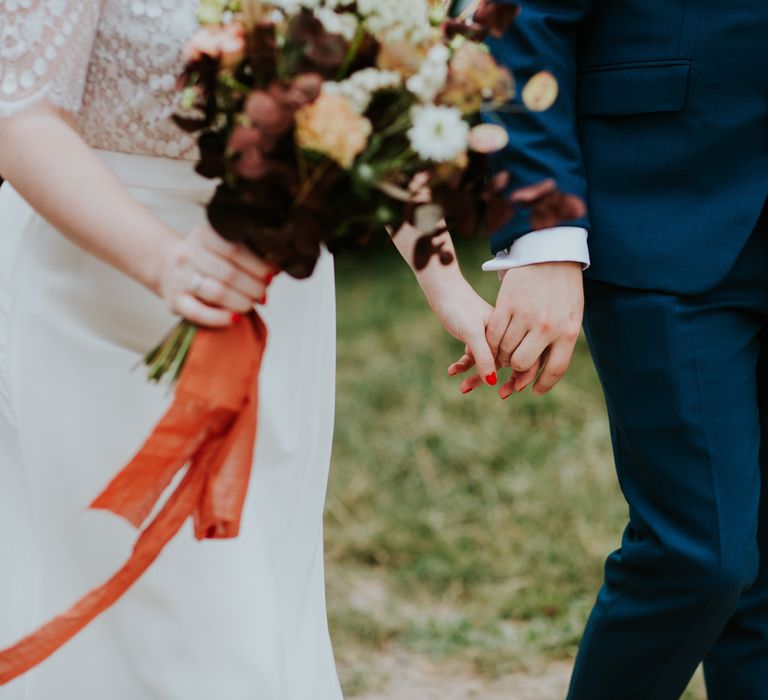 Bride holding her bouquet tied with orange ribbon 