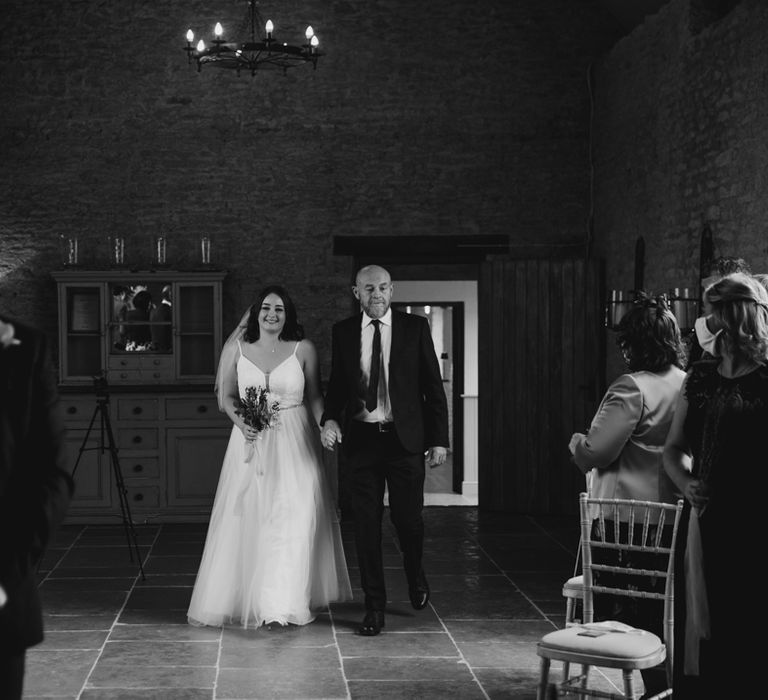 Smiling bride walking up the aisle with father