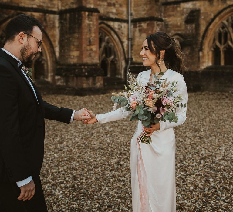 Groom holds brides hand during first look moment in school courtyard