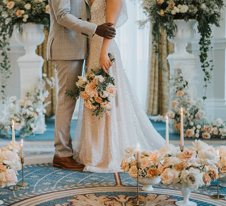 Peach and white wedding flowers arrangements and candles decorating the altar floor at The Landmark London 