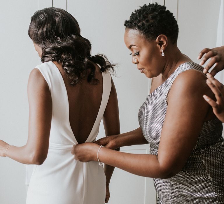 A family member helps zip up the back of a brides dress