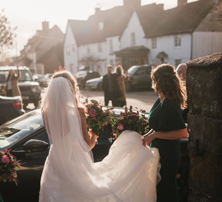 Bride stands with her back to the camera in the sunlight 