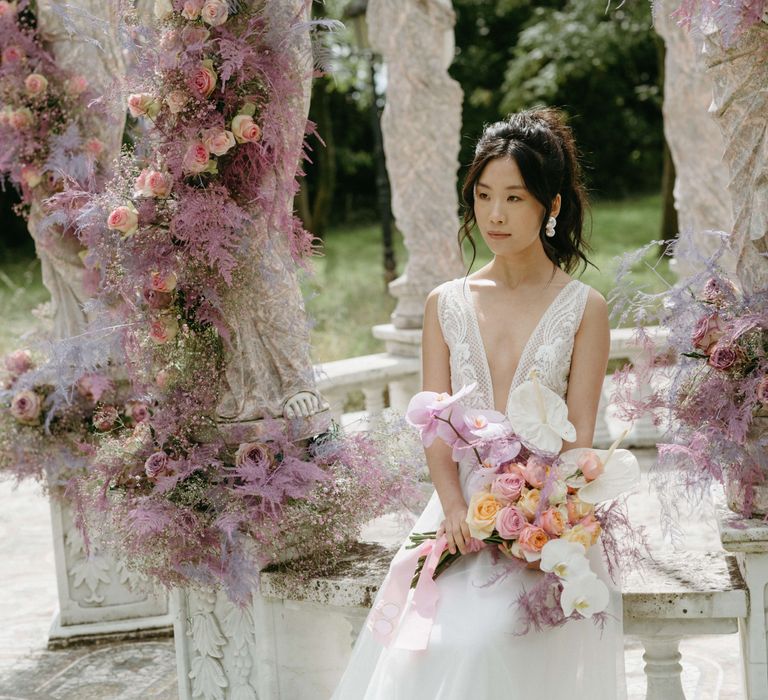 Bride sits within bandstand wearing low cut wedding gown