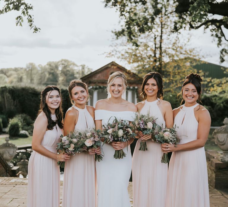 Bride stands with her bridesmaids who are wedding blush pink H&M dresses