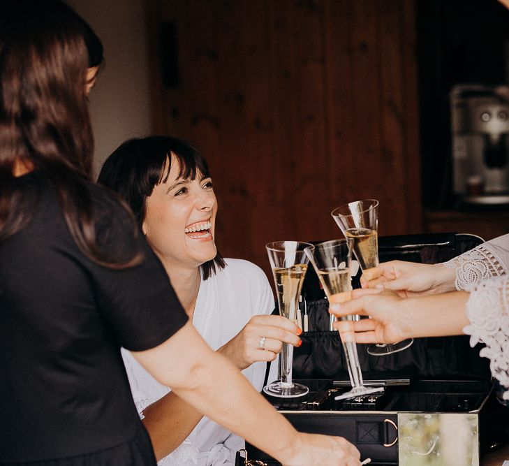 Bride and bridesmaids on the wedding morning sipping champagne 