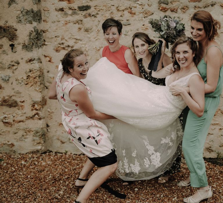 The bridesmaids lifting up the bride, all smiling and laughing