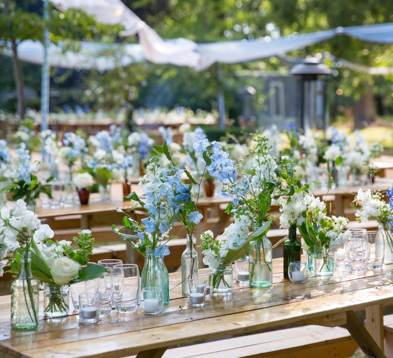 Blue and white flowers in jars lining banquet table - outdoor wedding ideas - Image courtesy of Marble Private