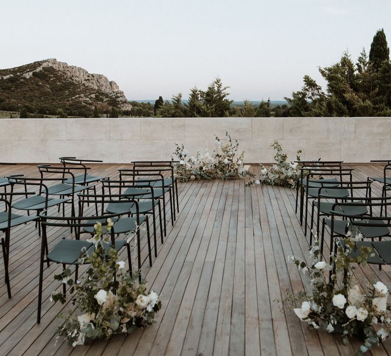 Minimalist wedding theme ceremony set up with aisle flowers and black metal chairs