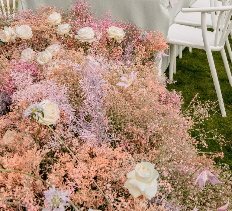 Pastel themed luxury wedding tablescape complete with white candles and large floral decor to the end of table